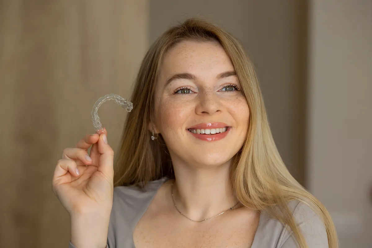A patient holding her clear aligner