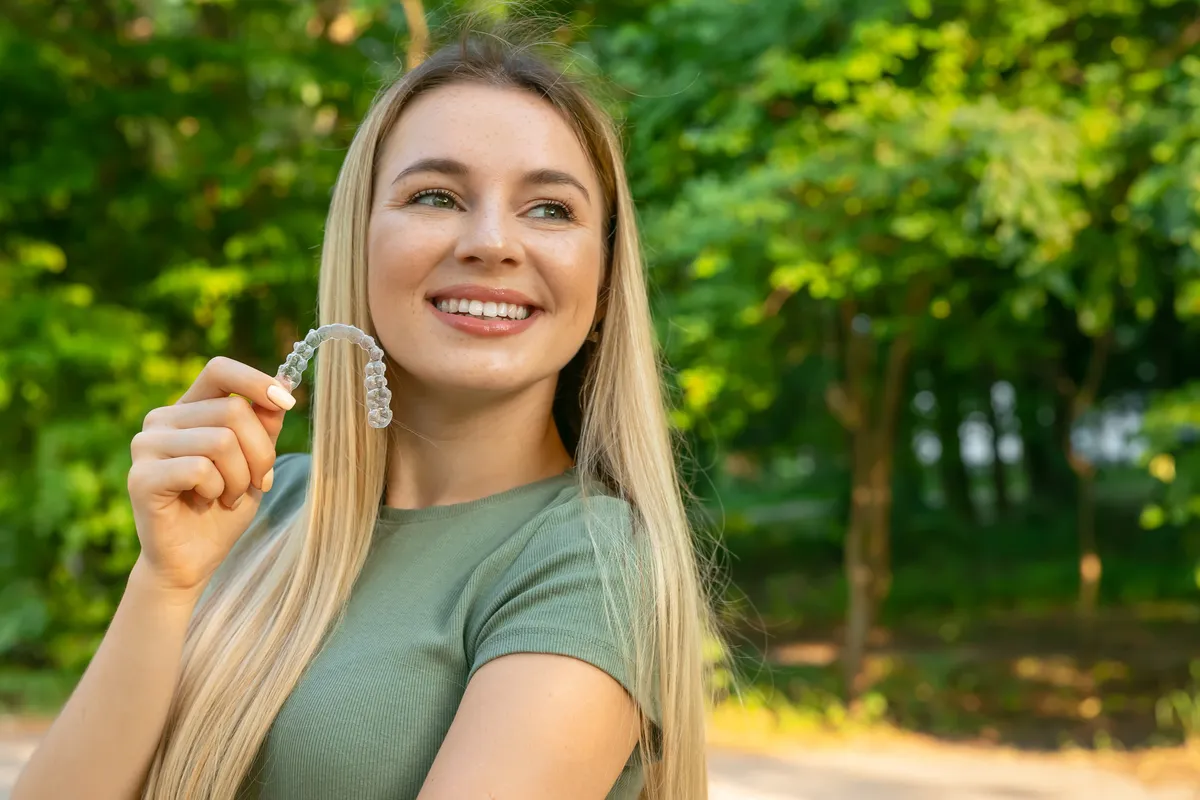 A patient holding her clear aligner outdoors