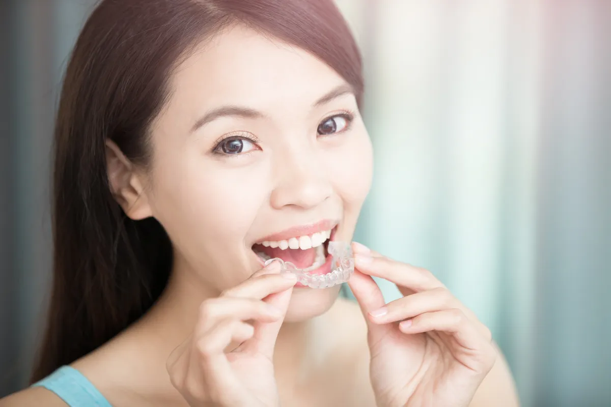 A patient inserting her clear aligner