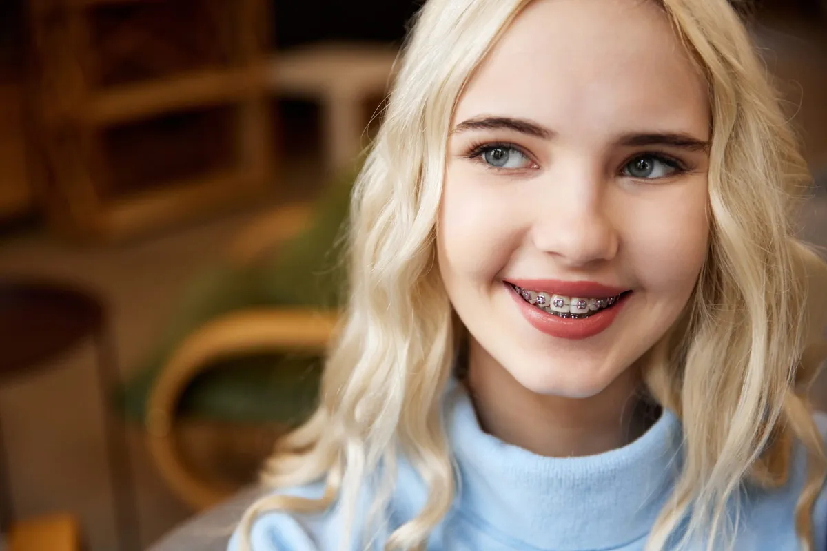 A teenager smiling confidently while wearing metal braces